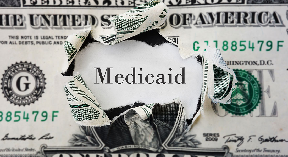 A dollar bill ripped open with the word Medicaid in between.