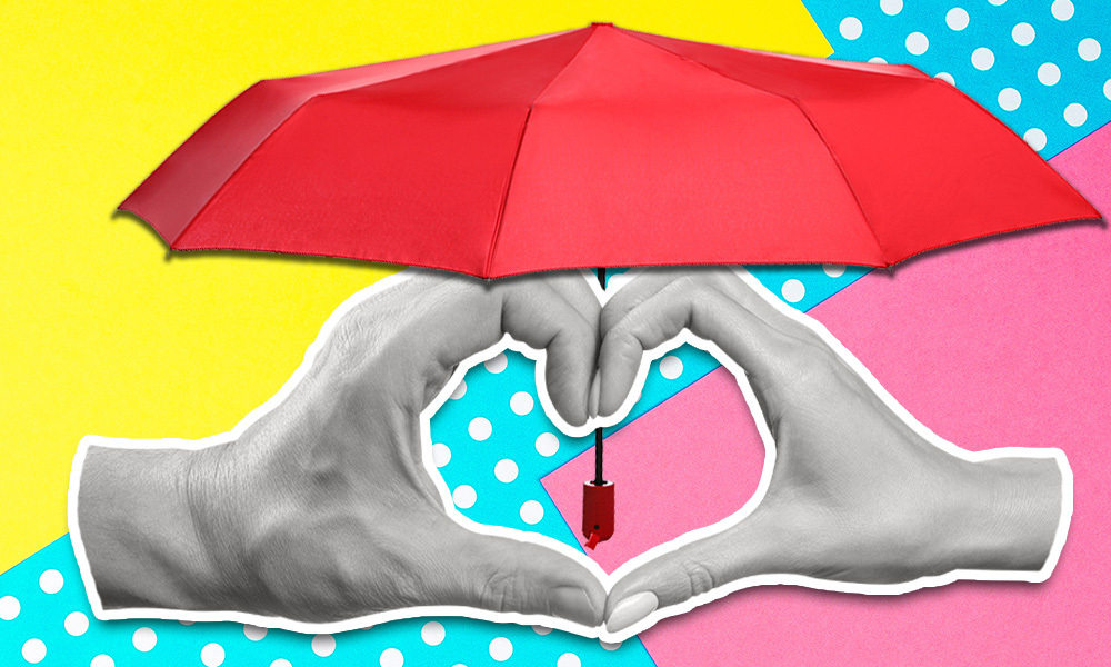 hands making the shape of a heart covered by an umbrella