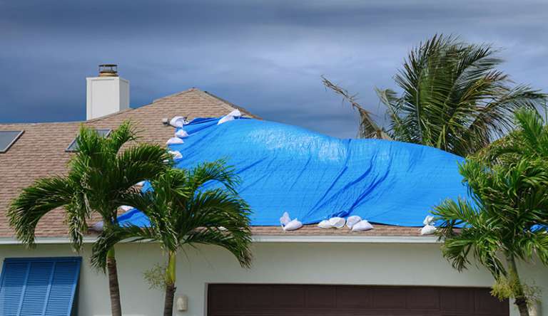 Estate Plan - Storm damage to the roof of a home covered by a blue tarp