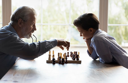 a grandfather playing chess with his per stirpes beneficiary who is his direct lineal descendant grandson