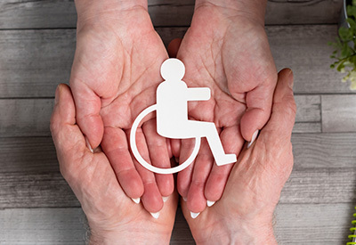 two sets of hands holding a cutout of the handicap symbol