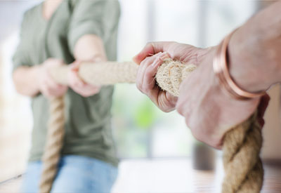 Two family members playing tug of war with a thick rope.