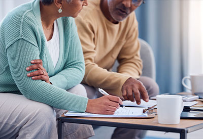 An elderly couple sits closely together at a table, reviewing estate planning documents.