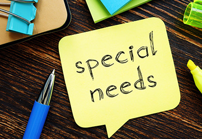 A sticky note with 'special needs' written on it, placed on a desk with office supplies, indicating special needs estate planning, revocable living trusts, and inheritance considerations for beneficiaries with disabilities.