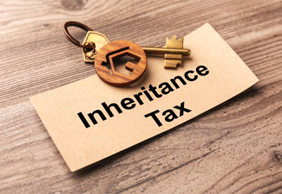 Key with a house-shaped keychain placed on a card labeled 'Inheritance Tax'