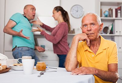 a concerned man sitting in front of an arguing couple