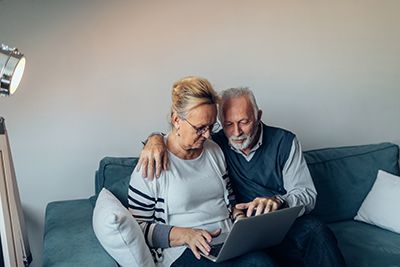Older couple sitting on couch looking at a laptop together