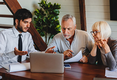 A financial advisor or attorney discussing documents with an older couple at a table, highlighting the importance of reviewing and updating estate plans.