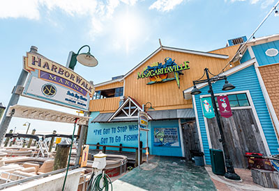 A colorful marina scene featuring the Margaritaville restaurant, inspired by the laid-back vibes of the Jimmy Buffett estate, with a wooden exterior and nautical decor.