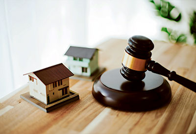 A wooden gavel rests on a table next to two small model houses, evoking thoughts of estate planning in a legal or real estate context.