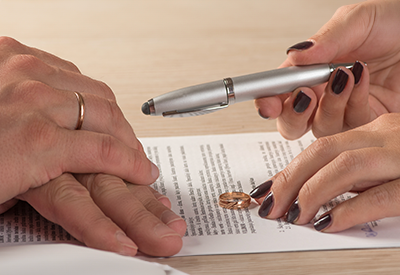 A couple signs legal documents with wedding rings on the table, representing estate legal challenges, estate protection, and the division of assets in second marriage estate planning.