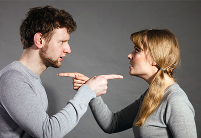 A man and woman face each other, both pointing and seemingly arguing, perhaps about blended families and step-children.
