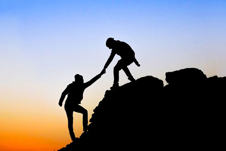 a person helping another person up a mountain signifying not doing your estate plan alone