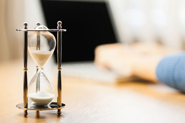an hourglass sitting on a table to signify avoiding delay with estate planning 