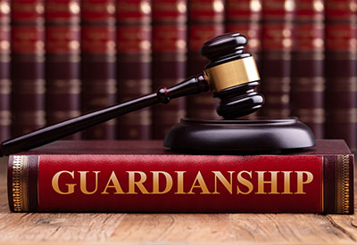 A judge's gavel rests on a thick red book titled 'Guardianship' in gold letters.
