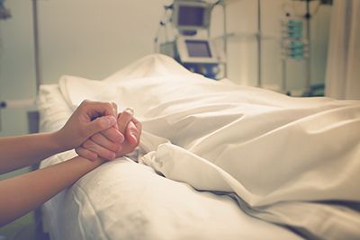 Guardianship - Person holding hands with another person in a hospital bed