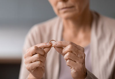 A woman gently holds a wedding ring, symbolizing a surviving spouse navigating rights and benefits after the loss of a veteran.