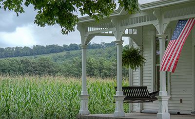 Retirement - Front porch swing with a corn field off to the side of the house