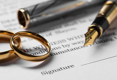A close-up of two gold wedding rings on a document labeled 'Signature' reflects the elegance of commitment. A fountain pen with a gold nib rests nearby