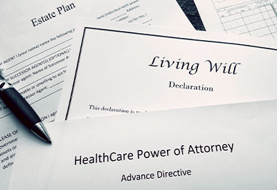 A close-up of estate planning documents, such as a Living Will, HealthCare Power of Attorney, and Estate Plan, with a pen resting on top