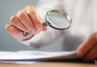a person look at documents through a magnifying glass