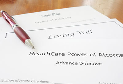 A close-up of several documents on a table, including 'Estate Plan,' 'Living Will,' and 'HealthCare Power of Attorney.'