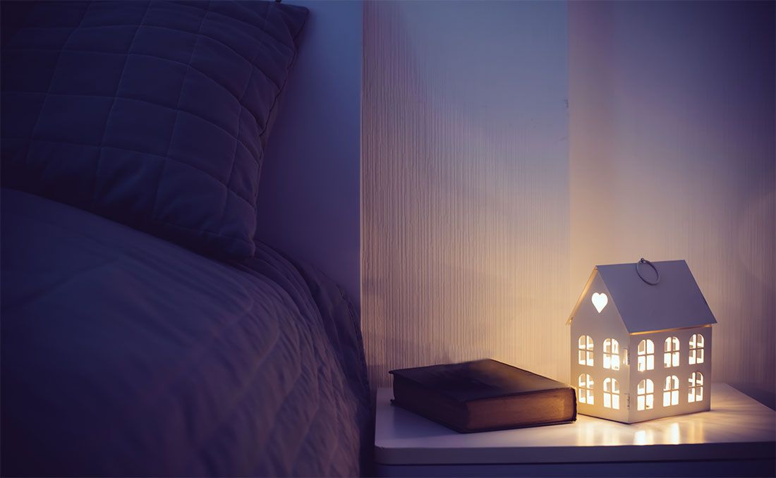 a nightstand with a book and a lamp on top