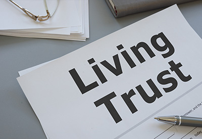 A document titled 'Living Trust' rests on a table beside reading glasses and a pen, an essential part of estate planning.