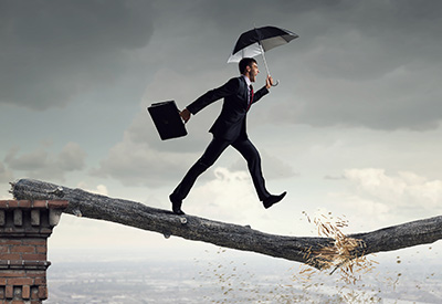 A businessman crossing a precarious gap on a breaking branch symbolizes the risks of trust funding mistakes and improper asset transfers.