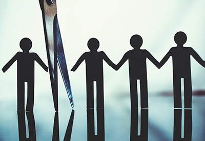 cissors cutting through paper cutouts of people, representing the separation of assets for Medicaid eligibility and inheritance protection.
