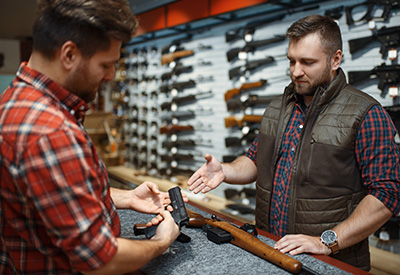 Two men in a gun store discussing a firearm transfer, representing legal firearms transactions and estate planning for heirs.