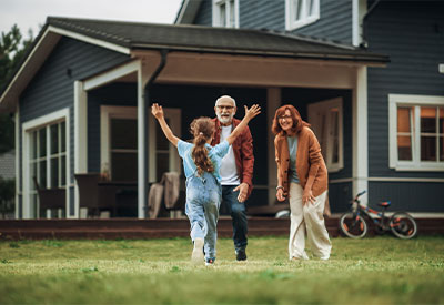 A young girl with long hair runs toward an elderly couple with open arms.