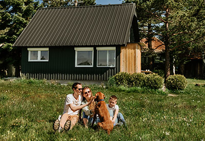 A happy family with their dog in front of their cabin held in a trust, property management, and family legacy planning.