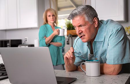 an older couple that appears to be stressed while looking at tax problems on their laptop