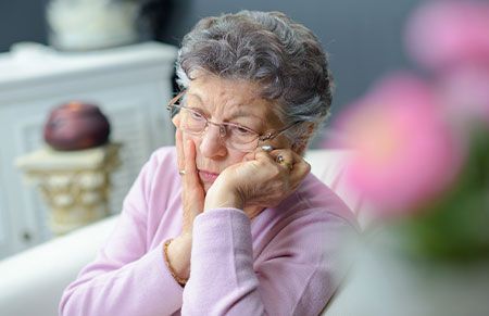 a sad widowed woman resting with her hands on her face