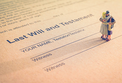 A miniature family standing on a 'Last Will and Testament' document