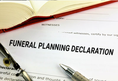 A funeral planning declaration form with a pen and an open book, emphasizing the need for proper documentation to prevent family disputes over funeral arrangements.