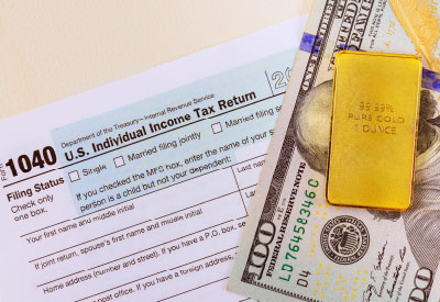A U.S. tax return form alongside a gold bar and cash, symbolizing inheritance tax and gold bar transfer tax.