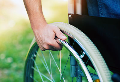 Close-up of a person’s hand gripping the wheel of a wheelchair