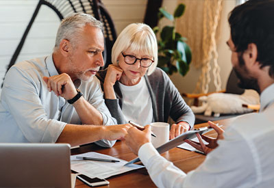 n elderly couple attentively reviews estate planning documents at a wooden table, guided by a younger person