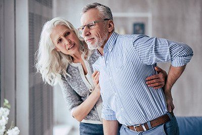 Estate Plan - Senior man experiencing back pain and his wife comforting him
