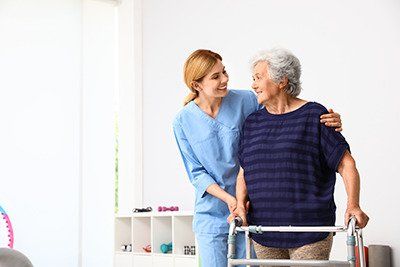 Nurse assisting a senior woman on medicaid with a walker